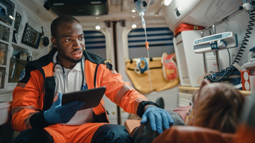EParamedic gets information from patient A Black EMS Professional Paramedic using a tablet fills in a questionnaire for an injured patient.